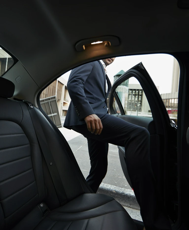 mężczyzna w&nbsp;garniturze wsiadający do&nbsp;taksówki